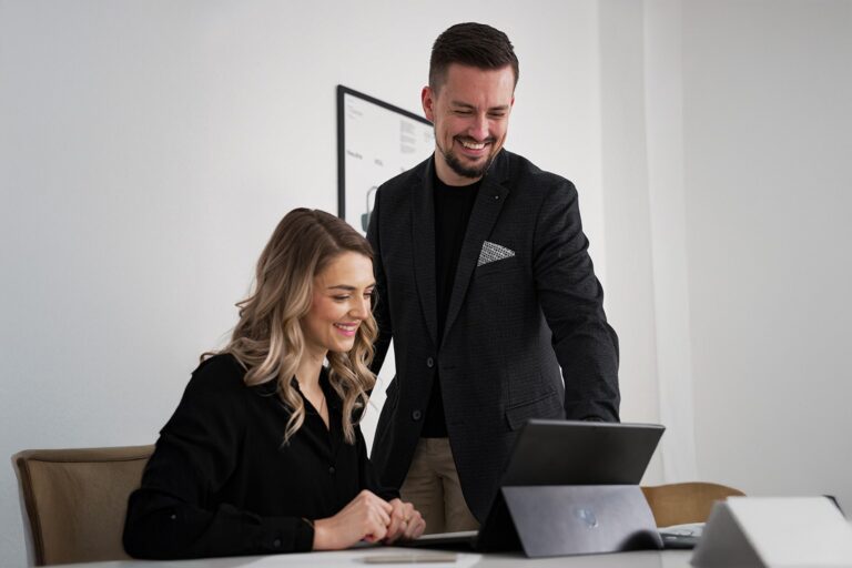 Johann Steinwand mit kundin am laptop, beide schauen lächelnd ergebnisse am laptop an