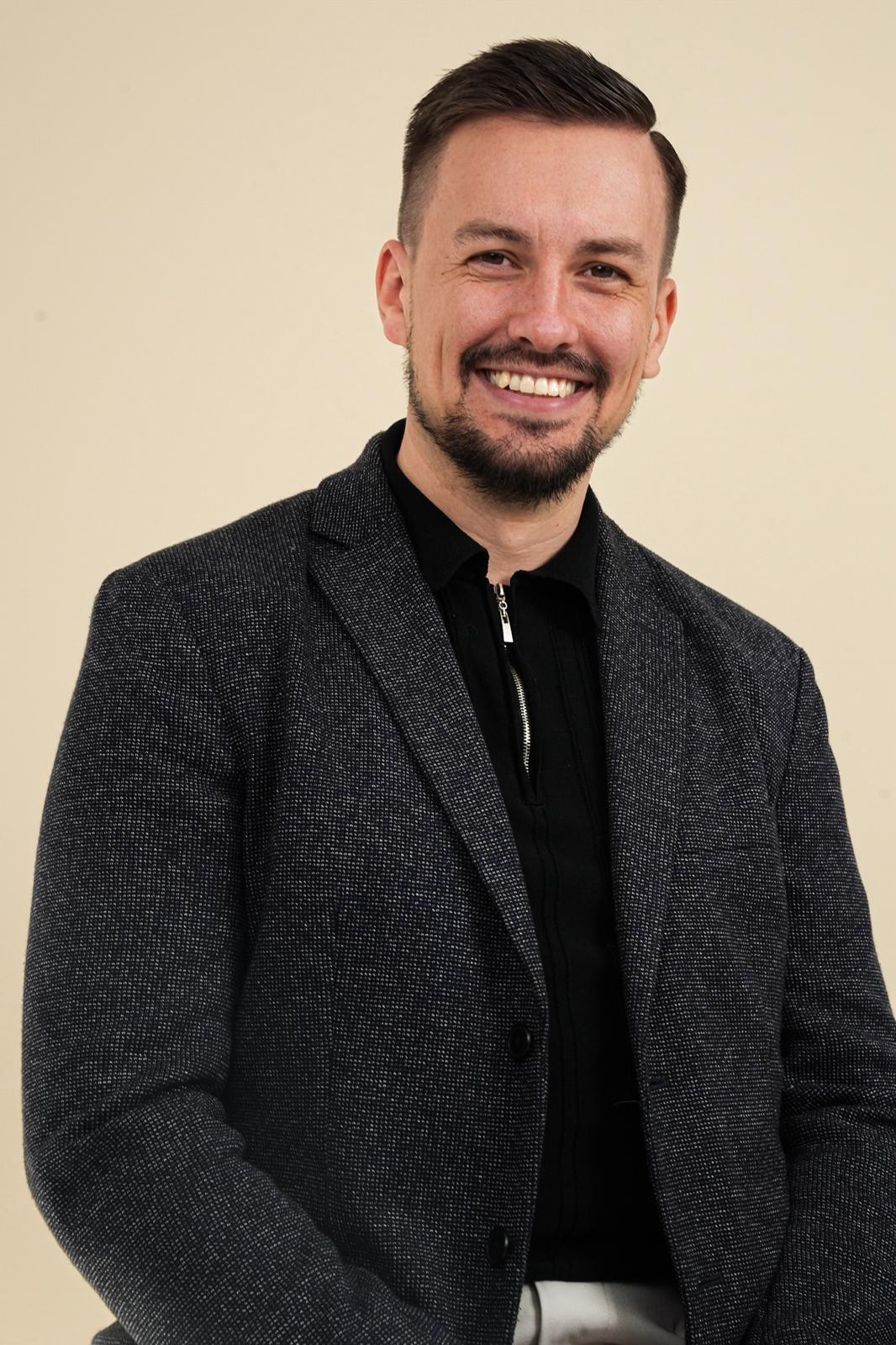 Foto von Johann Steinwand mit Jacket und Poloshirt, sitzend und lächelnd